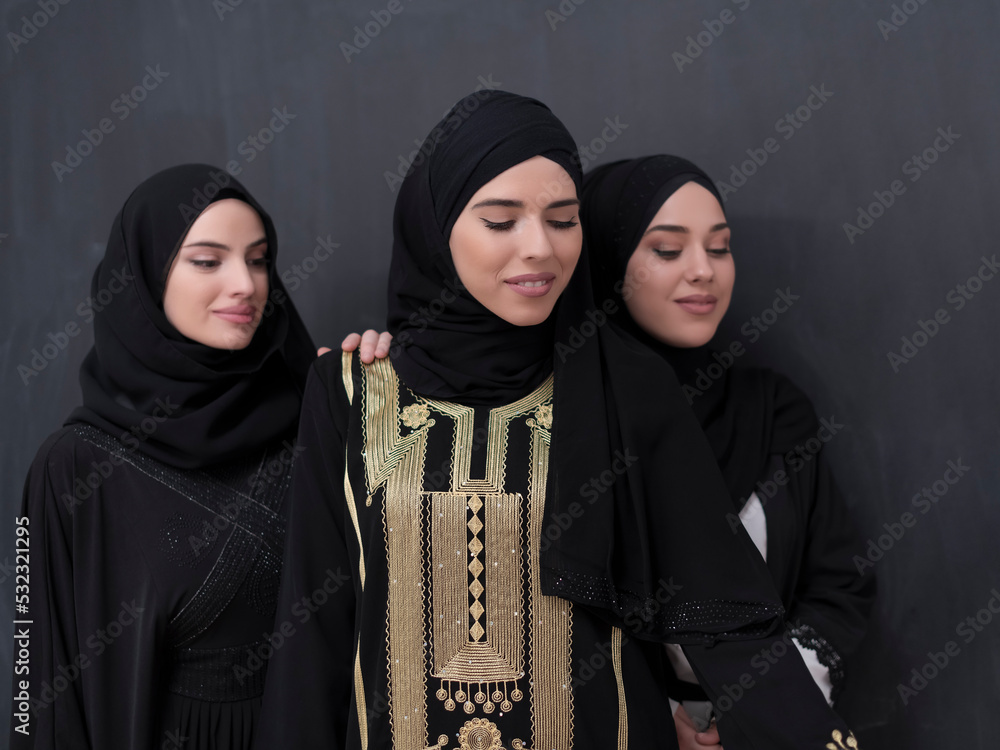 Group portrait of beautiful Muslim women in a fashionable dress with hijab isolated on black background Group portrait of beautiful Muslim women in a fashionable dress with hijab isolated on black background