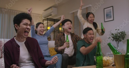 Group of young adult friend man and woman asia people sit at sofa couch joy night party fun game match world cup live TV at home eat snack bowl drink beer bottle glass jump mad happy win exult face