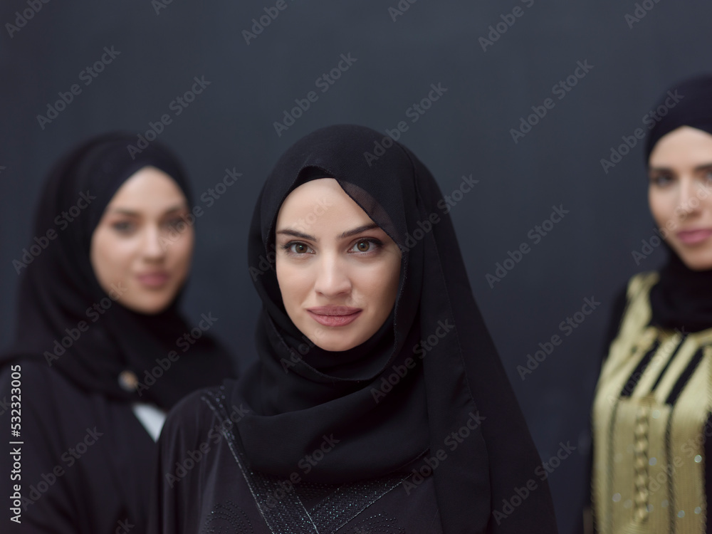 Group portrait of beautiful Muslim women in a fashionable dress with hijab isolated on black background Group portrait of beautiful Muslim women in a fashionable dress with hijab isolated on black background