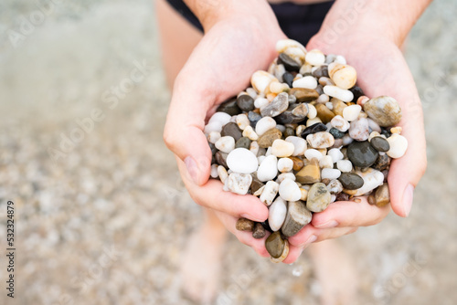 Stones in hand. A man on the beach holds a pebble in his hands. A man in swimming trunks at sea in the summer. 