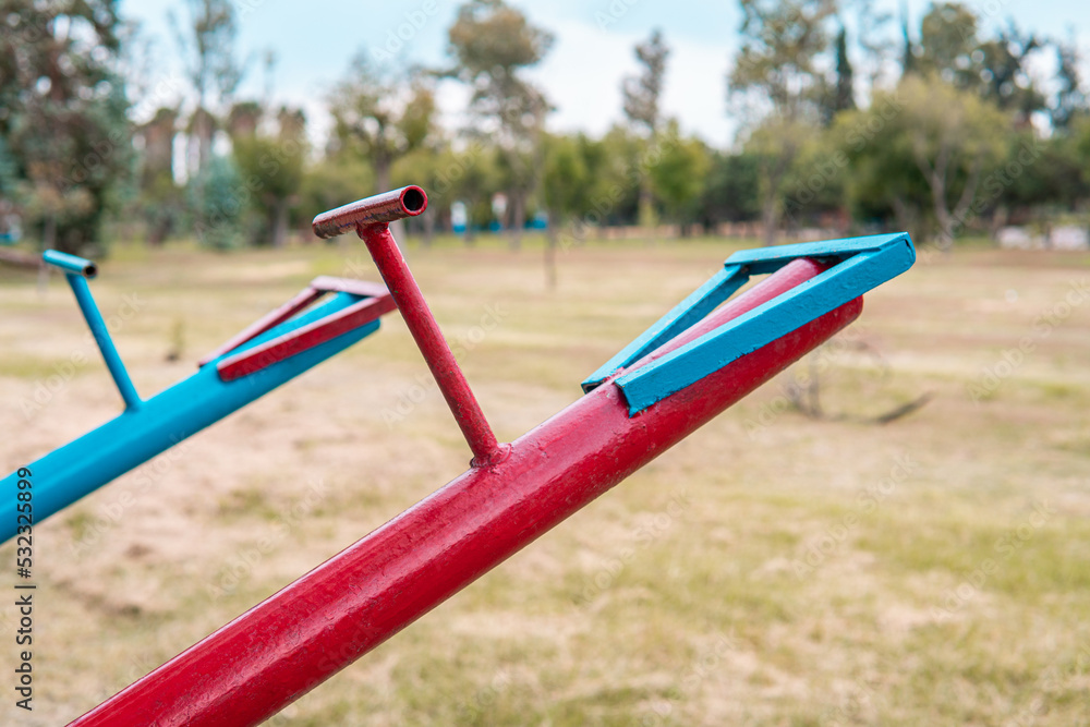 High quality photography. Blue and red swings in the empty park full of grass and nature. Park for children to play. High quality photography. Blue and red swings in the empty park full of grass and nature. Park for children to play.
