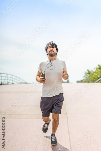 Portrait of handsome attractive mature bearded athletic latin man guy 40s in casual white t-shirt running in the street