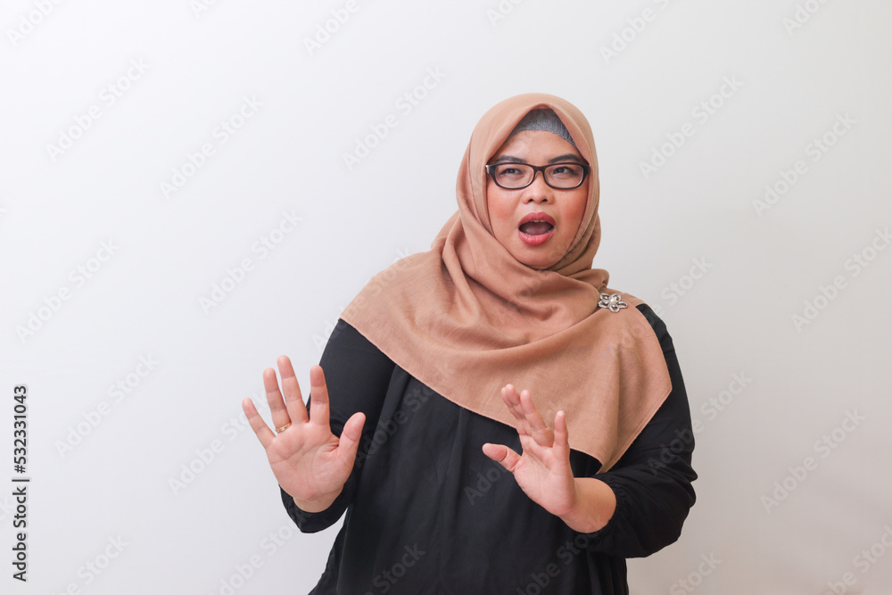 Portrait of cheerful Asian woman with hijab forming a hand gesture to avoid something. Advertising concept. Isolated image on white background Portrait of cheerful Asian woman with hijab forming a hand gesture to avoid something. Advertising concept. Isolated image on white background