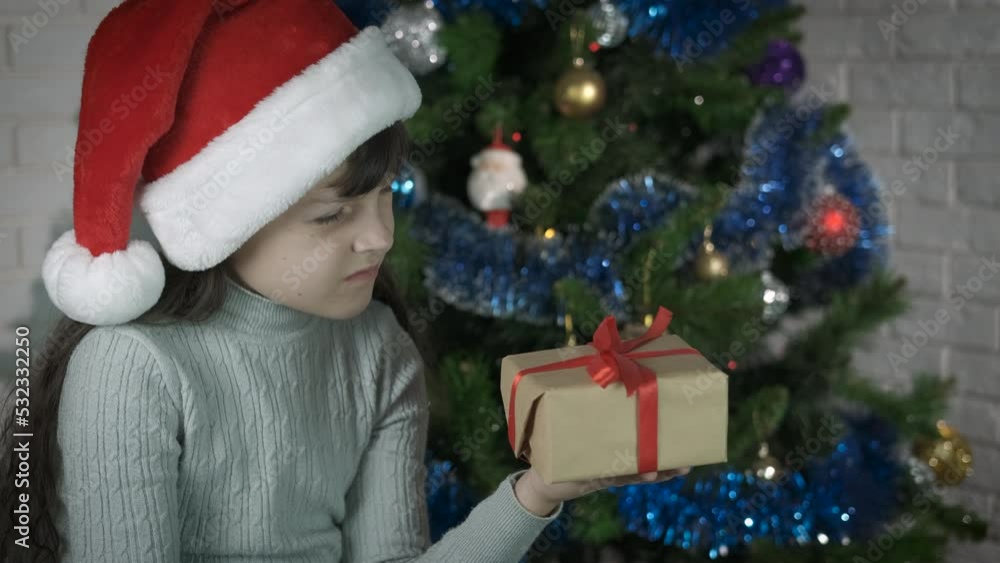 Child bad gift for New Year. Displeased little girl in santa hat with christmas present. Child bad gift for New Year. Displeased little girl in santa hat with christmas present.