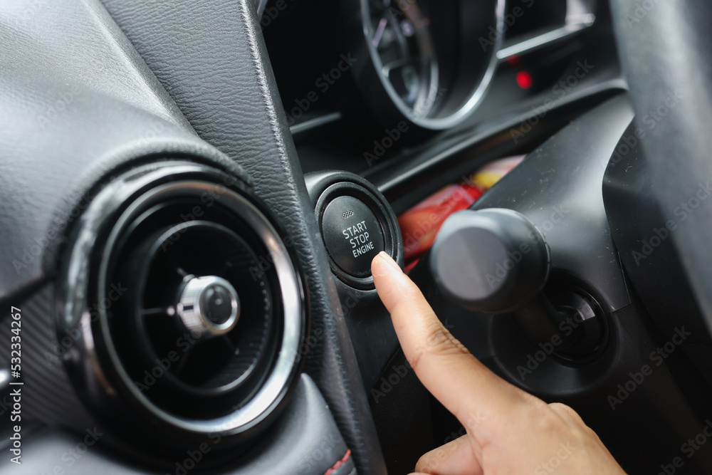 Car start stop system with finger pressing the button.finger pressing the Engine start stop button of a car.