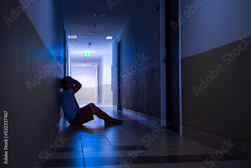 Wallpaper Mural Depressed man sitting on the floor with his head down, silhouette of stressed young man holding his head in the hallway Torontodigital.ca