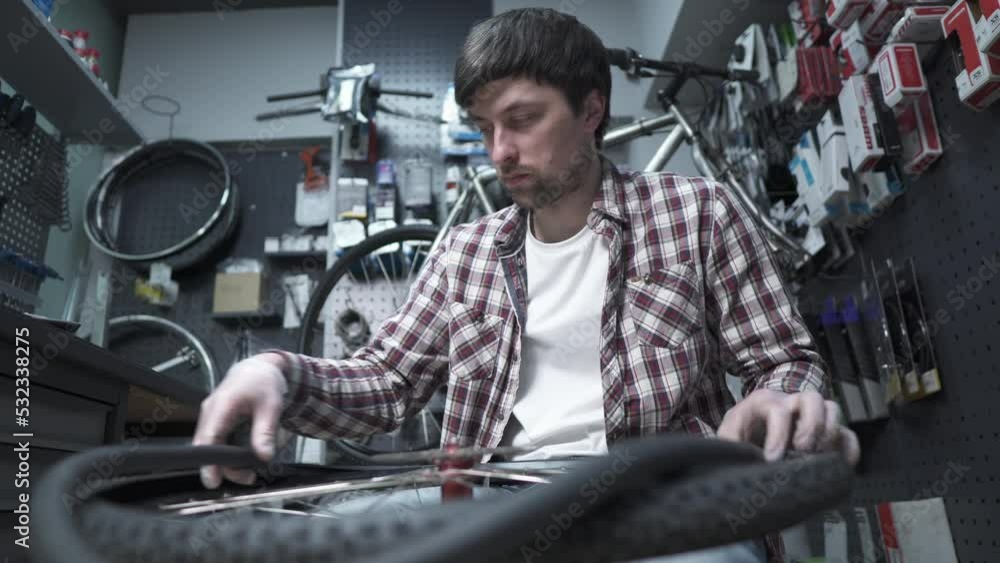 Replacing a bicycle tube and tire in a bicycle shop. Bicycle repairman at work fixing a wheel. Bicycle mechanic at work in a bike shop. Service and cycle repair and maintenance. Small business Replacing a bicycle tube and tire in a bicycle shop. Bicycle repairman at work fixing a wheel. Bicycle mechanic at work in a bike shop. Service and cycle repair and maintenance. Small business