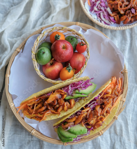 Homemade healthy snacks. Vegan Pulled Pork Taco Fold with Mixed Fruits Basket. Good for between meals snack, made from jackfruit flesh as pork, bbq sauce, purple cabbage, carrots taco shell photo