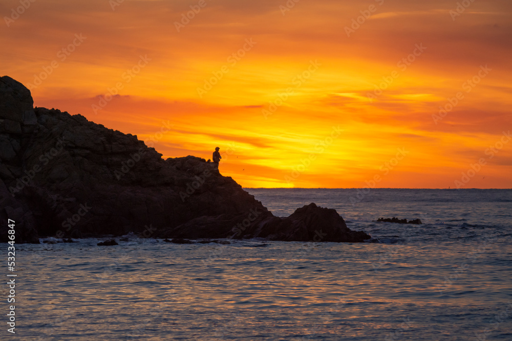 fishermen in a sunrise on the rocks in the sea