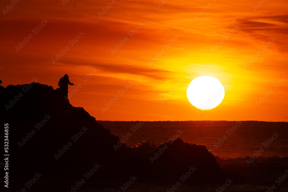 fishermen in a sunrise on the rocks in the sea fishermen in a sunrise on the rocks in the sea