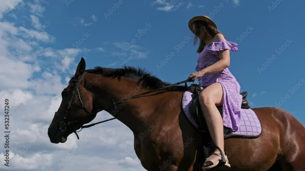 Video „Young woman in a summer dress and straw hat riding a horse in a