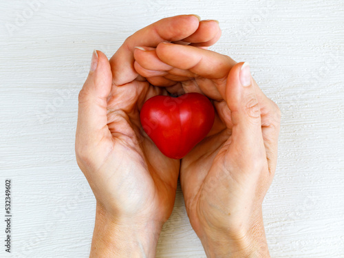 Fototapeta Naklejka Na Ścianę i Meble -  health, medicine and love, relationship, charity, donate, kind, world heart day concept - close up of female hands with small red heart on white background