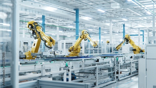 Large Production Line with Industrial Robot Arms at Modern Bright Factory. Solar Panels are being Assembled on Conveyor. Automated Manufacturing Facility