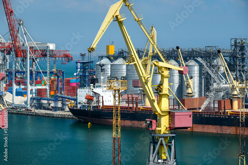 industrial seaport infrastructure  sea  cranes and dry cargo ship  grain silo and bulk carrier vessel  concept of sea cargo transportation