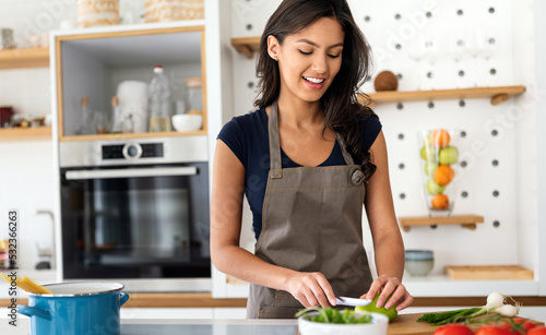 Woman making salad in kitchen smiling and laughing happy and cheerful.