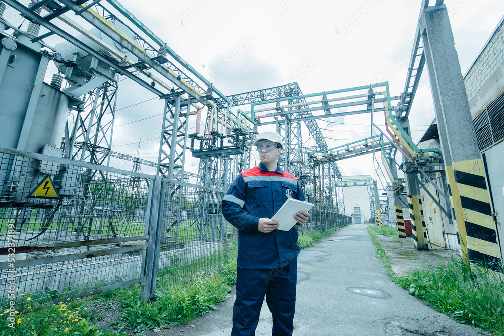 An energy engineer inspects the modern equipment of an electrical substation before commissioning. Energy and industry. Scheduled repair of electrical equipment.