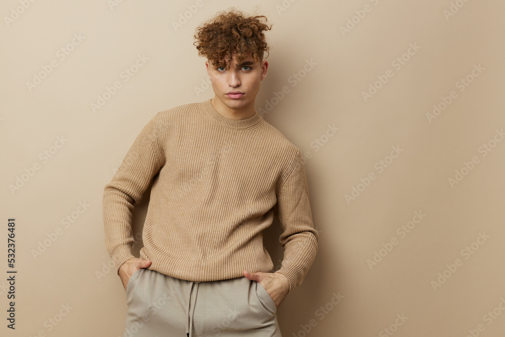 a handsome, attractive man in stylish clothes stands on a beige background and poses relaxed with his hands in his pockets. Horizontal Studio Photography a handsome, attractive man in stylish clothes stands on a beige background and poses relaxed with his hands in his pockets. Horizontal Studio Photography