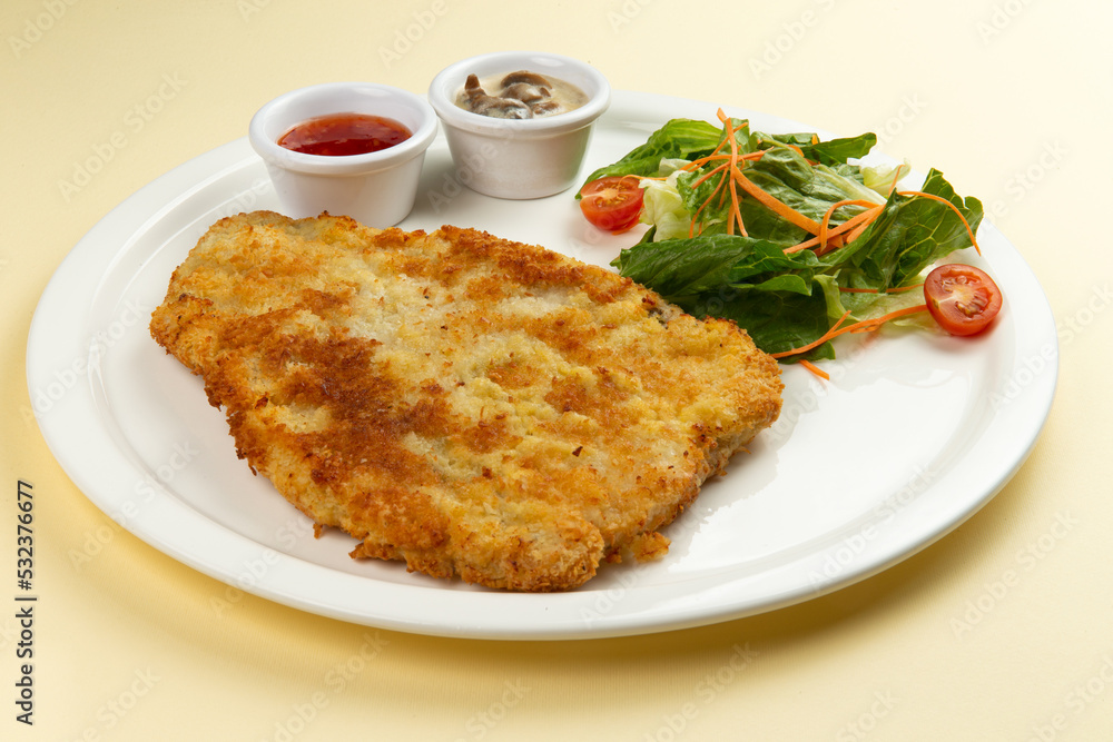 Turkey schnitzel and salad in a plate on a light background. Turkey schnitzel and salad in a plate on a light background.