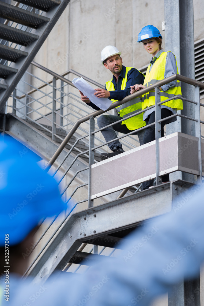 workers on elevated stairway talking to colleague on the ground workers on elevated stairway talking to colleague on the ground
