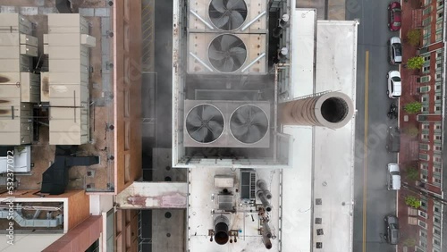 Smoke and steam escaping from factory captured by straight-down aerial shot. Smoke pollutes air next to residential townhomes. Carbon emission, pollution, industrial theme. photo