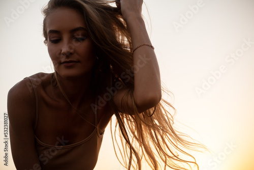 Beautiful woman with natural blond hairs posing in the nature against the field with dry grass and sky