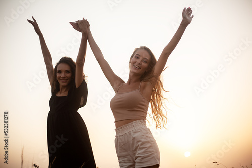 group pf two friends,  two thin girls spend happy time together in the nature. Beautiful overweight and strong women have fun, enjoy the momet of sunset . photo