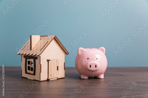 Home model and piggh bank on a table.