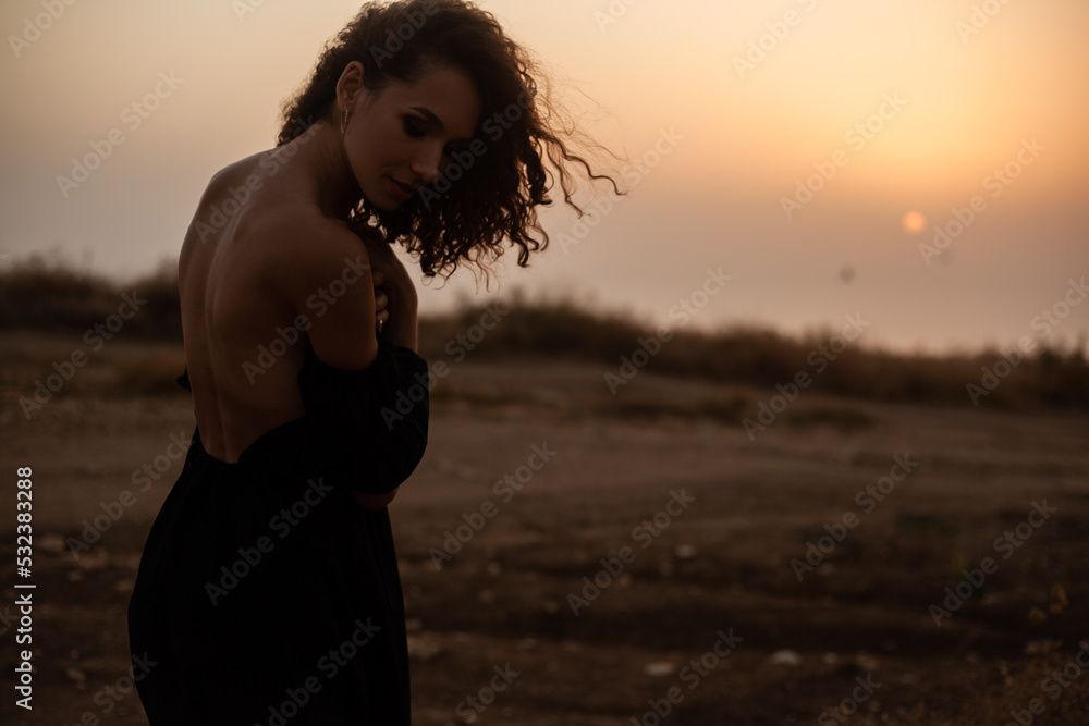 Portrait Beautiful sexy woman with natural curly hairs posing in the nature against  the field with dry grass and sky