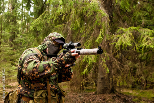 Russian soldier sniper man dressed military disguise camouflage uniform with weapon in woodland at nature background, looking. Male border guard in country border with rifle on war. Copy text space