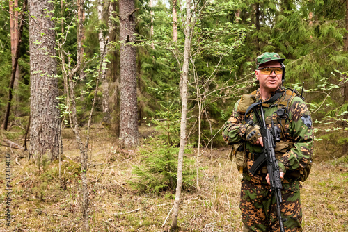 Ukrainian soldier man dressed military camouflage uniform with weapon at nature background, looking away. Male border guard in country border with autogun on war. Copy text space