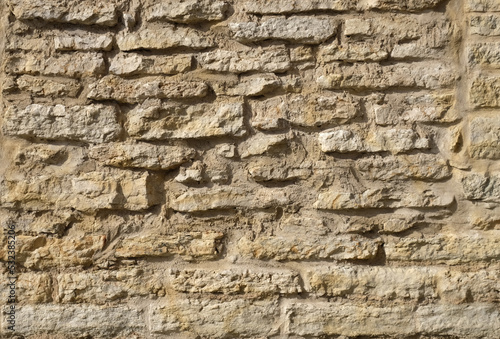 Texture of a beige stone wall. Smooth, cracked surface. Old castle wall of stone different shape. Part of a stone wall, for background or texture. 