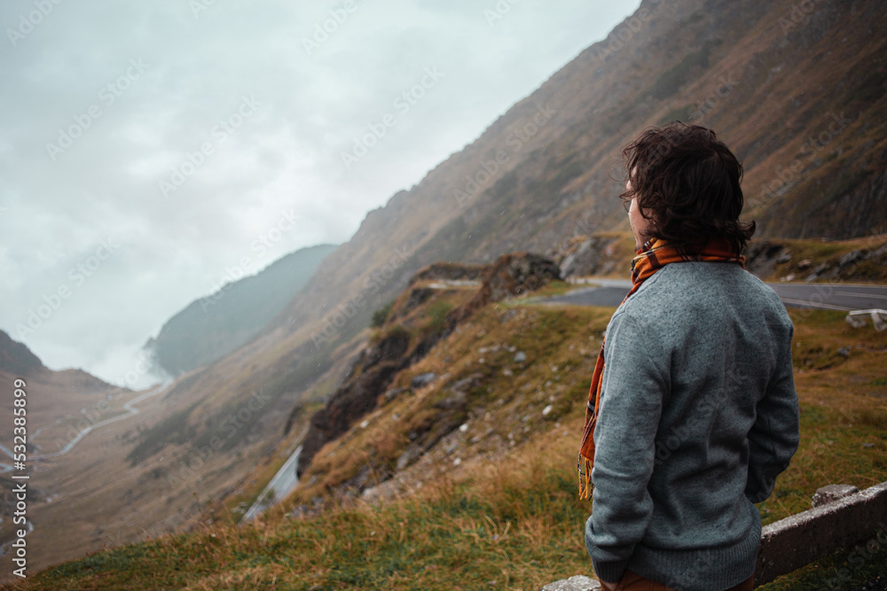 man stands on road in mountains in Romania, Carpathians. concept of loneliness, freedom, melancholy and thoughtfulness. Autumn, rain and fog, nature, outdoors. Man and nature, landscape,