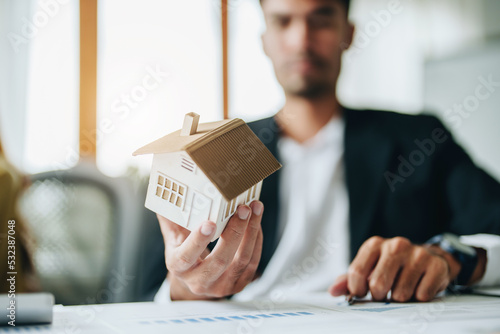 portrait of a customer holding a house model shows a lot of thought in managing borrowing risks for homes photo