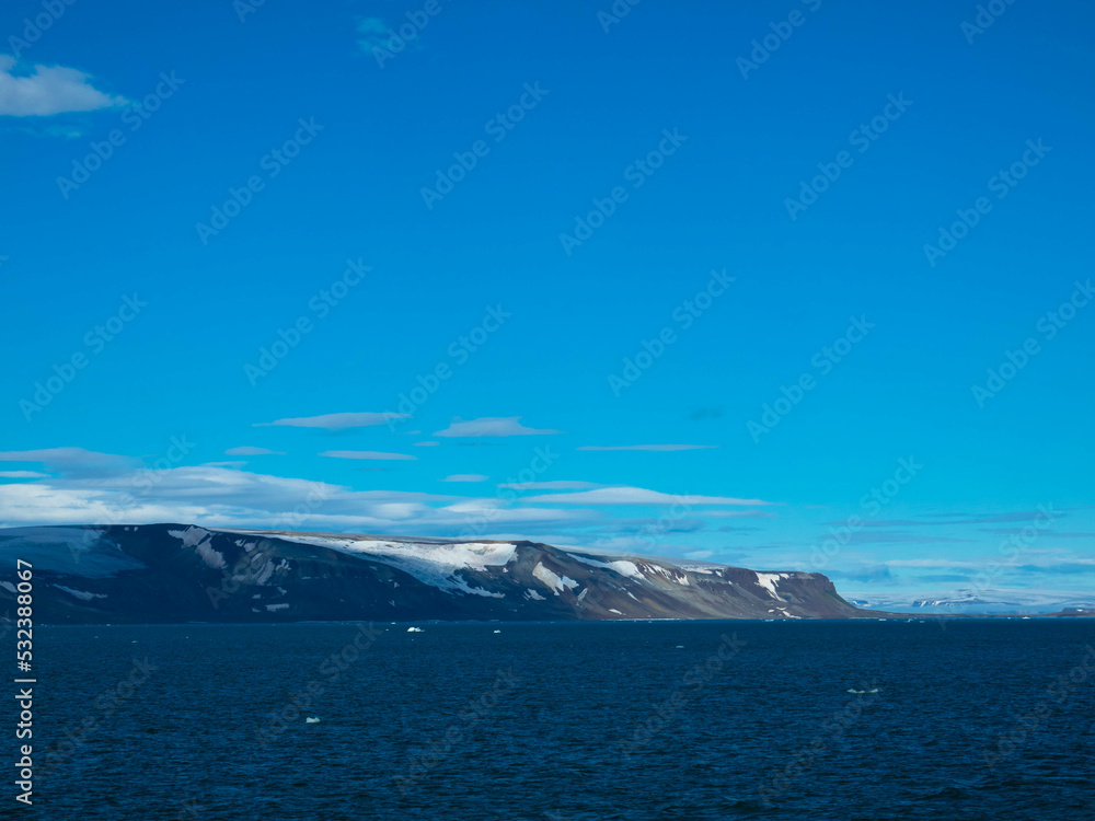 Spectacular panorama view of Wilhelmoya island with mountain range and blue sky. Torellneset, Nordaustlandet  
Spitsbergen, Norway. Tourism and vacations concept.