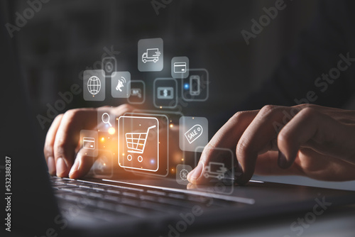 Young man using laptop with shopping cart icon,  Online shopping and e-commerce concept.