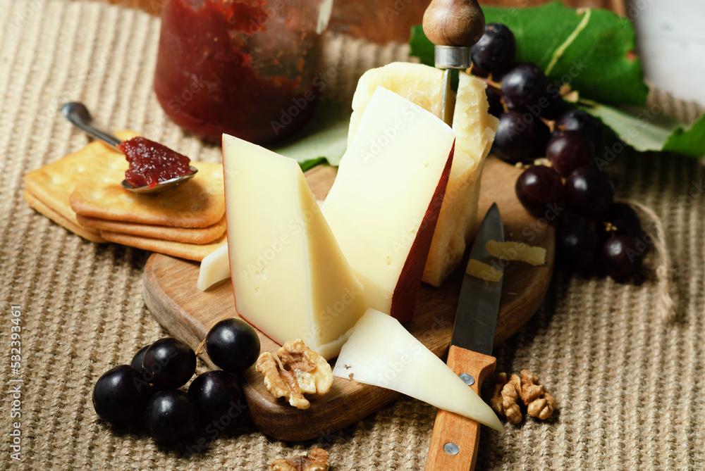 Fontal Italian pasteurized cow's milk cheese with black grapes, jam and nut on a rustic