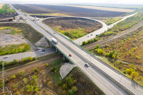 Road junction with a bridge. Cars drive on the roads. Aerial view of road intersection with traffic on city streets. White Truck with goods Moving on Highway Road intersection junction. photo