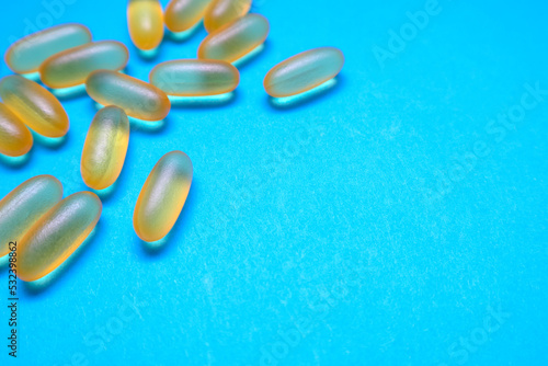 Capsules of fish fat oil  omega 3  vitamin e on the blue background with copy space. Healthcare  vitamins  supplements daily intake concept.