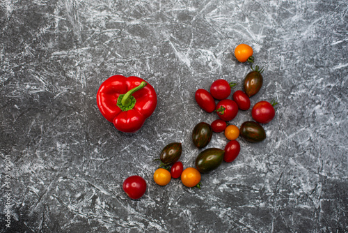Red paprika peppers on a black and white background next to delta red brown burgundy tomatoes healthy food fresh vegetables bright food vegan background for a menu site in restaurant top view flat lay