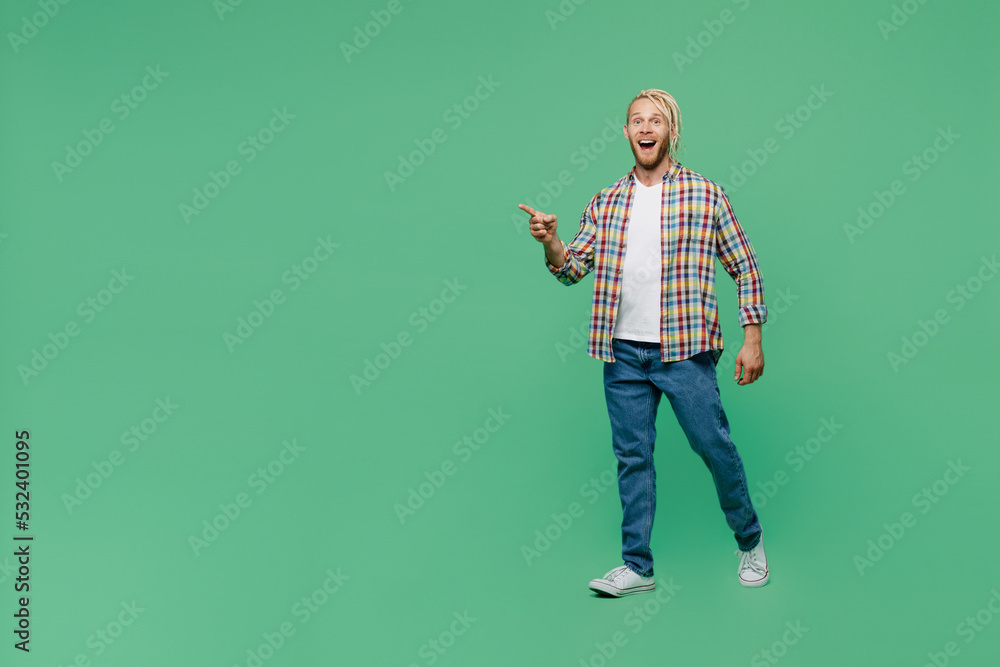 Full body young happy blond man with dreadlocks 20s he wear casual shirt walking going strolling point index finger aside on workspace isolated on pastel plain light green background studio portrait. Full body young happy blond man with dreadlocks 20s he wear casual shirt walking going strolling point index finger aside on workspace isolated on pastel plain light green background studio portrait.