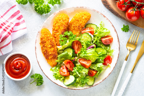 Chicken nuggets with green vegetable salad and ketchup sauce at white table. Healthy food. Top view image with copy space,