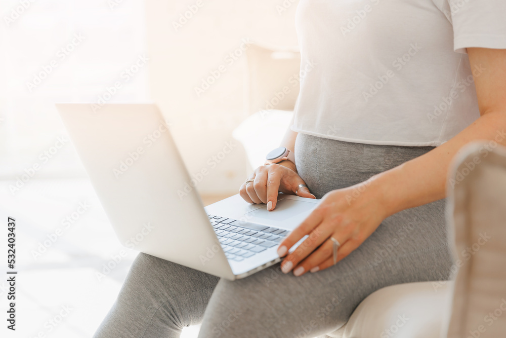 Closeup hand of pregnancy woman using online laptop on sofa with sunlight Closeup hand of pregnancy woman using online laptop on sofa with sunlight