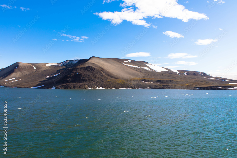 Spectacular panorama view of Wilhelmoya island with mountain range and blue sky. Torellneset, Nordaustlandet  
Spitsbergen, Norway. Tourism and vacations concept.