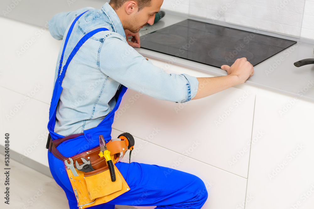 a worker repairs an electric stove, Induction Stove. a worker repairs an electric stove, Induction Stove.