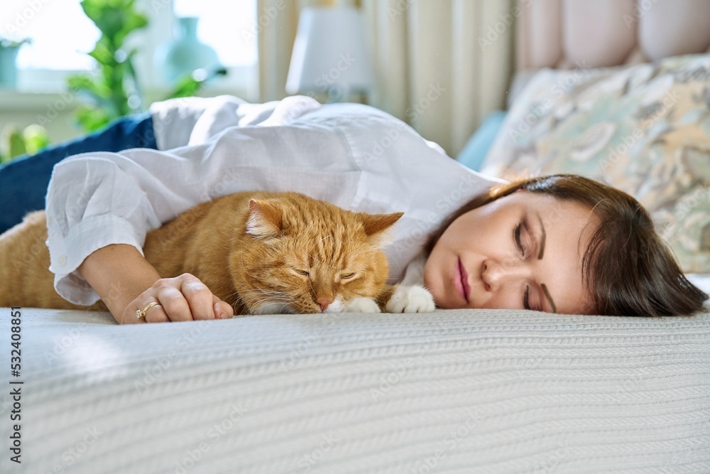 Middle aged woman sleeping with big ginger cat on bed Middle aged woman sleeping with big ginger cat on bed