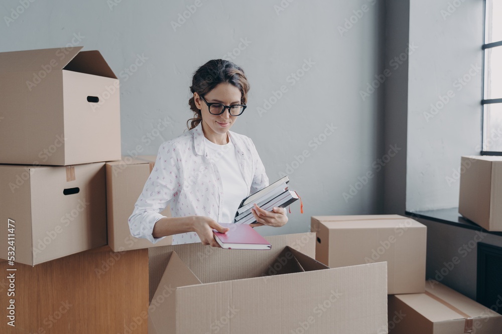 Businesswoman packs things in cardboard boxes on moving day, preparing for relocation in new office Businesswoman packs things in cardboard boxes on moving day, preparing for relocation in new office