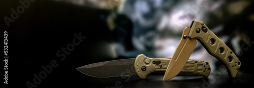 Khaki military pocket folding knives. Compact metal sharp knife with a folding blade. Blurred back. photo