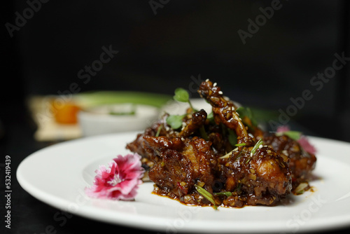 Szechuan Chicken which is a popular Indo-Chinese non vegetarian recipe. served in a plate with chilli sauce
