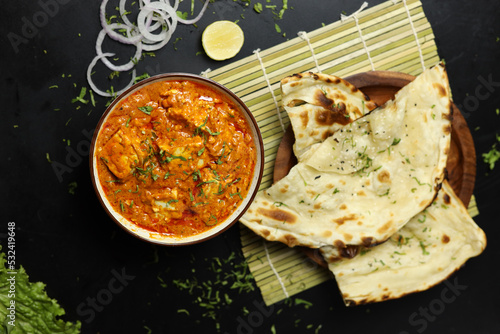 Paneer Butter Masala served with naan bread,onion rings and lemon, on a black background with space for text , Indian Curry photo