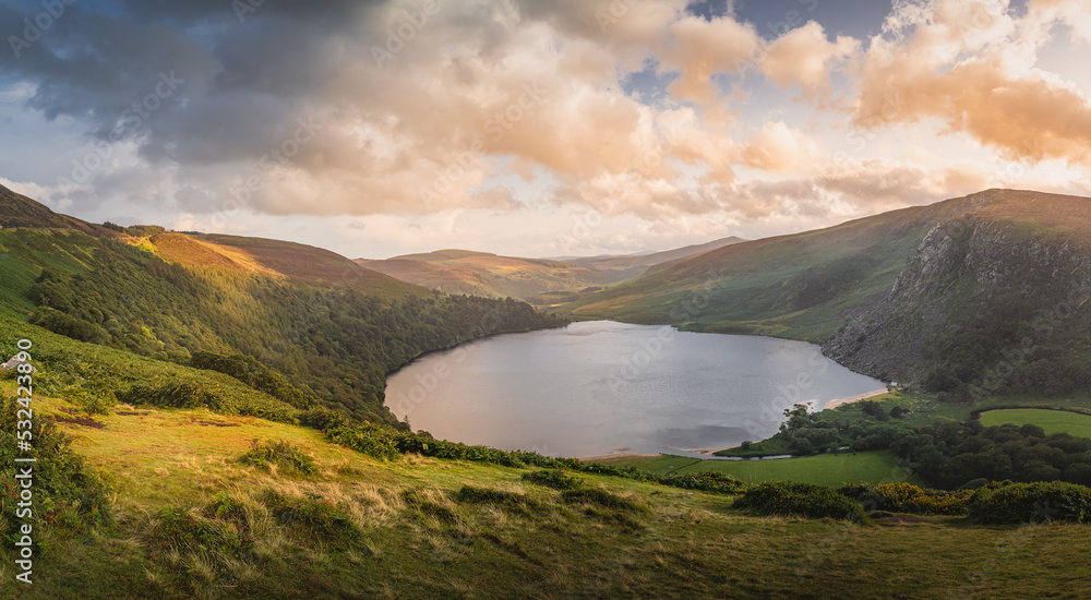 Beautiful panorama with dramatic sunset at Lough Tay, called The Guinness  Lake located in deep valley and surrounded by Wicklow Mountains, Ireland  Stock Photo